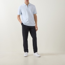 Model wearing Boss Black Casual H Pei Logo Zip Polo Shirt in Open Blue with half-zip placket, styled with dark trousers and white trainers.