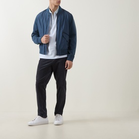 Model wearing Boss Black Casual H Pei Logo Zip Polo Shirt in Open Blue, styled with a navy bomber jacket, black trousers and white trainers.
