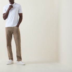 Model wearing Boss Black Casual H-Phillipson Logo Polo Shirt in white with tipped trims, styled with tan chinos and white trainers.