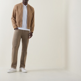 Model wearing Boss Black Casual H-Phillipson Logo Polo Shirt in white, styled with camel bomber jacket, tan chinos and white trainers.