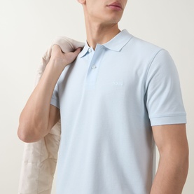 Model wearing Boss Black Casual Open Blue cotton polo shirt with short sleeves and button placket, carrying jacket over shoulder.