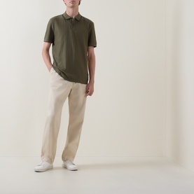 Model wearing Boss Black Casual Parlay Polo Shirt in Open Green with textured finish, styled with beige trousers and white trainers.