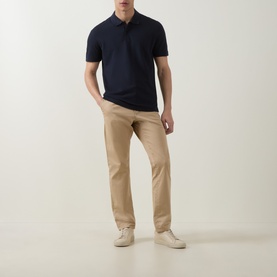 Model wearing Boss Black Casual Parlay Logo Polo Shirt in dark blue with two-button placket, styled with beige chinos and cream trainers.