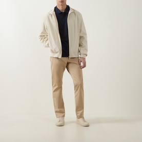 Model wearing Boss Black Casual Parlay Logo Polo Shirt in dark blue, styled with cream zip-up jacket, beige chinos and white trainers
