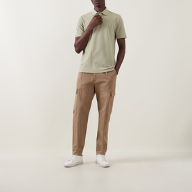 Model wearing Boss Black Casual Dark Beige cotton polo shirt, styled with tan cargo trousers and white trainers.