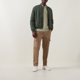 Model wearing Boss Black Casual Dark Beige cotton polo, styled with olive quilted bomber jacket, tan cargo trousers and white trainers.