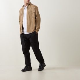 Model wearing Boss Black Casual Parris Logo Shirt in white, styled with tan overshirt, black trousers and black trainers.