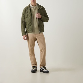 Model wearing Boss Black Casual dark beige cotton polo, styled with olive quilted jacket, beige chinos and monochrome chunky trainers.