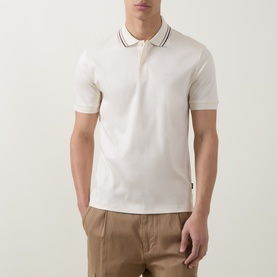 Model wearing Boss Black Casual Penrose Tipped Logo Polo Shirt in Open White with stripe-tipped collar, styled with tan trousers.