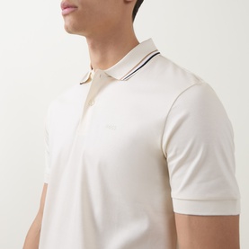 Model wearing Boss Black Casual Penrose Tipped Logo Polo Shirt in Open White with stripe-tipped collar and two-button placket.