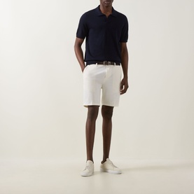 Model wearing Boss Black Casual Open White cotton-elastane shorts with brown belt, styled with navy polo shirt and white trainers.