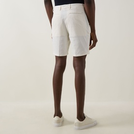 Model wearing Boss Black Casual Open White cotton-blend shorts, rear view, styled with white trainers.