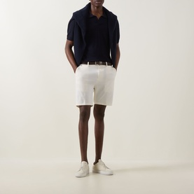 Model wearing Boss Black Casual Open White cotton shorts with belt, styled with navy polo shirt and white trainers.