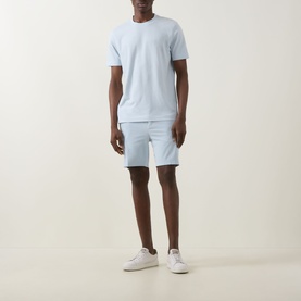 Model wearing Boss Black Casual Open Blue cotton-elastane shorts, styled with a matching light blue T-shirt and white trainers.