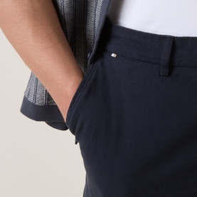 Model wearing Boss Black Casual dark blue cotton shorts, close-up of front pocket with signature logo flag detail