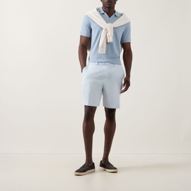 Model wearing Boss Black Casual Peter C Drawstring Shorts in Open Blue, styled with a light blue polo shirt and cream sweater tied at the shoulders.