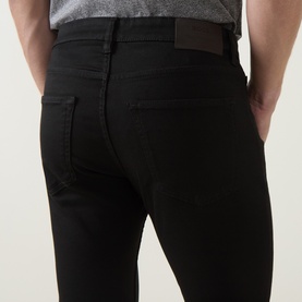 Model wearing Boss Black Casual H-Delaware Slim-Leg Jeans in black, showing rear view with five-pocket styling and branded patch detail.