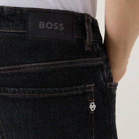 Model wearing Boss Black Casual charcoal straight jeans, close-up of back pocket with branded leather patch and logo rivet detail.