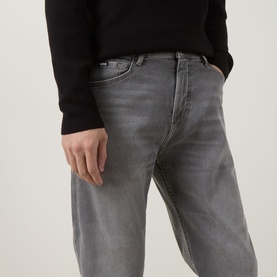 Model wearing Boss Black Casual medium grey straight jeans with faded wash detail, styled with a black knit top.