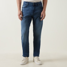 Model wearing Boss Black Casual P-Re.Maine Slim-Leg Jeans in dark blue mid-wash stretch denim, styled with white trainers.