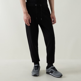 Model wearing Boss Black Casual black cotton-blend sweat bottoms with drawstring waist, styled with grey trainers.