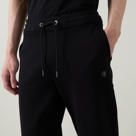 Model wearing Boss Black Casual black cotton-blend joggers with drawstring waist and small logo detail on thigh