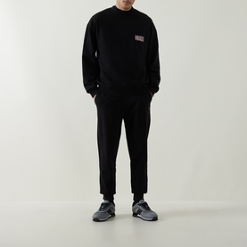 Model wearing Boss Black Casual black sweat bottoms with matching black sweatshirt, styled with grey trainers.