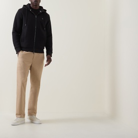Model wearing Boss Black Casual black zip-through hoodie with beige chinos and white trainers.