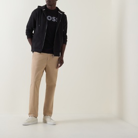 Model wearing Boss Black Casual black zip-through hoodie, styled with logo tee, beige chinos and white trainers.