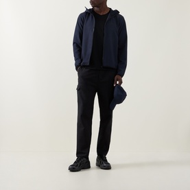 Model wearing Boss Green Label dark blue casual jacket with zip fastening and hood, styled with black cargo trousers and trainers.