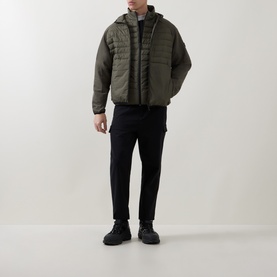 Model wearing Boss Green Label Urbanex Hybrid Quilted Jacket in Open Green, styled with black trousers and black boots.