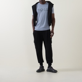 Model wearing Boss Green Label Dark Grey Crew Neck T-Shirt with black gilet, black cargo joggers and dark chunky trainers.