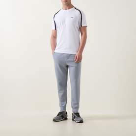 Model wearing Boss Green Label Contrast Insert Active Logo T-Shirt in white with navy stripe inserts, styled with grey joggers and trainers.