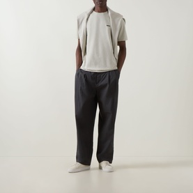Model wearing Boss Green Label Swing Printed Logo T-Shirt in Light Beige, styled with dark charcoal trousers and white trainers.