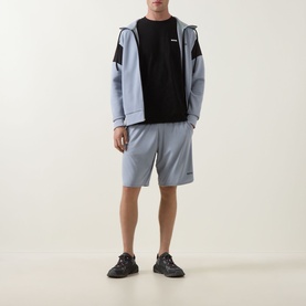 Model wearing Boss Green Label black crew neck T-shirt with grey zip-up hoodie, grey shorts, and dark trainers.