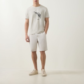Model wearing Boss Green Label Light Beige crew neck T-shirt with graphic print, styled with matching shorts and cream trainers.