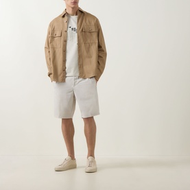 Model wearing Boss Green Label Light Beige crew neck T-shirt, styled with sand overshirt, grey shorts, and cream suede shoes.