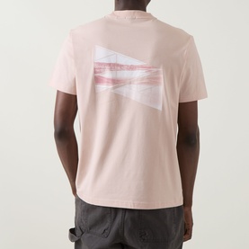 Model wearing Boss Green Label pastel orange crew neck T-shirt, back view showing abstract graphic print, styled with dark trousers.