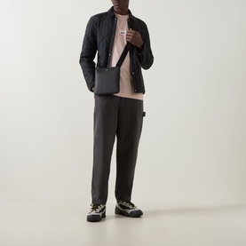 Model wearing Boss Green Label Light/Pastel Orange crew neck T-shirt, styled with black quilted jacket, dark trousers, and chunky trainers.