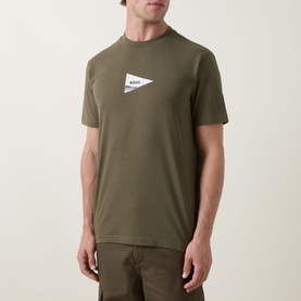 Model wearing Boss Green Label Crew Neck T in Open Green with white triangle logo patch on chest, paired with khaki trousers