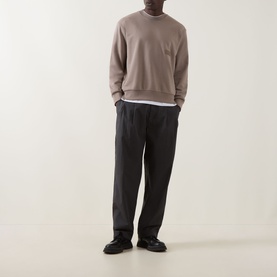 Model wearing Boss Green Label SW Logo Patch Sweatshirt in light pastel green with dark trousers and black shoes.