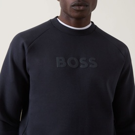 Model wearing Boss Green Label Salbo Logo Sweatshirt in dark blue, crew neck with tonal embossed logo, styled with white crew neck underneath