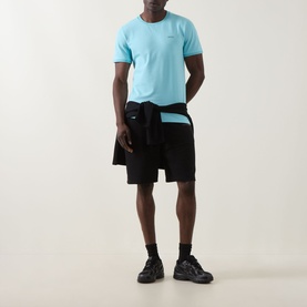 Model wearing Boss Green Label Taul Logo T-Shirt in Open Blue with black shorts and black trainers