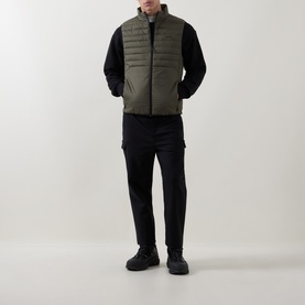 Model wearing Boss Green Label Urbanex Hybrid Gilet in Open Green, styled with black long-sleeve top, cargo trousers and chunky boots.