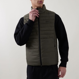 Model wearing Boss Green Label Urbanex Hybrid Gilet in Open Green, zip fastening, styled with black long-sleeve top and trousers