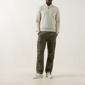 Model wearing Boss Green Label Logo Half-Zip Sweatshirt in Light Beige with olive cargo trousers and white trainers.