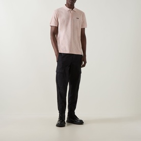 Model wearing Boss Green Label Swing Printed Logo Polo Shirt in light pastel orange with black cargo trousers and black boots.