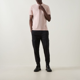 Model wearing Boss Green Label Swing Printed Logo Polo Shirt in Light Pastel Orange with black cargo trousers and black boots