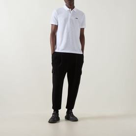 Model wearing Boss Green Label Swing Printed Logo Polo Shirt in white with black cargo trousers and black trainers