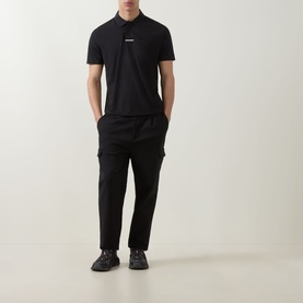 Model wearing Boss Green Label black polo shirt with small chest logo, styled with black cargo trousers and dark trainers